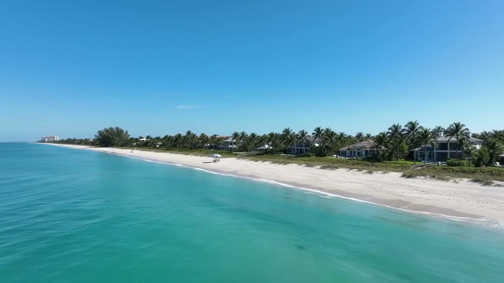 Aerial view of a Southwest Florida beach with turquoise Gulf water, white sand and palms